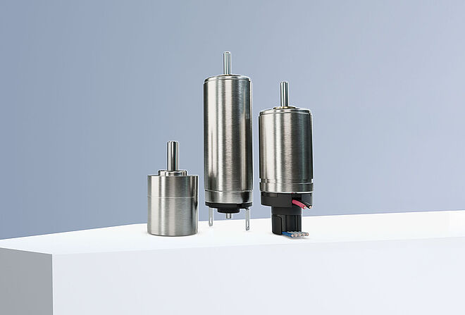 直径为 14 mm 的 FAULHABER 直流电机、减速机和编码器 - 滑块 两台来自 FAULHABER SXR 和 GXR 产品系列的直流电机以及一个编码器和一个来自 GPT 产品系列的减速机排列在灰蓝色背景下的白色台阶上。